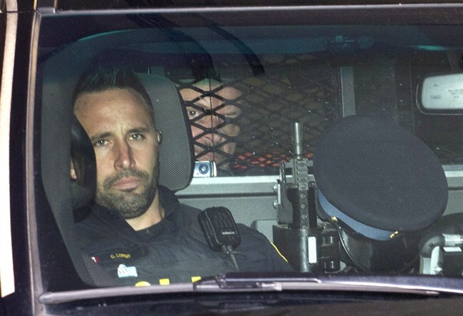 Basil Borutski looks out from behind the mesh enclosure in the back of a police vehicle after appearing at the courthouse in Pembroke, Ont. on Wednesday, Sept. 23, 2015.