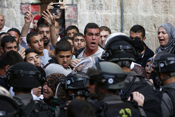 Palestinians shout in front of Israeli security forces who block a road leading to the Al-Aqsa mosque compound in Jerusalem's Old City on September 13, 2015.