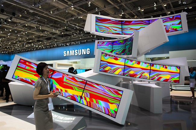 This is a Friday, Sept. 5, 2014 file photo of a woman as she passes an installation with curved screens, displayed by Samsung at the consumer electronic fair IFA in Berlin, Germany. Europe’s flagship gadget show, the IFA in Berlin, opens its doors to the public on Friday Sept. 4, 2015 . Almost 1,500 companies and over 250 000 people are expected to visit the event, which runs through Sept. 9.
