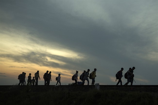 This is a Thursday Sept. 3, 2015 file photo of a group of refugees as they walk along the railway tracks near the town of Roszke, Hungary, after crossing the border from Serbia.
