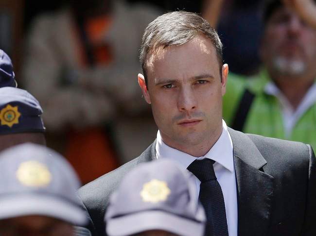 FILE - In this Friday, Oct. 17, 2014 file photo, Oscar Pistorius is escorted by police officers as he leaves the high court in Pretoria, South Africa. 