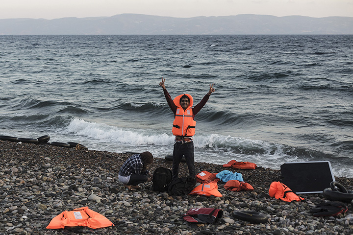 A Syrian refugee flashes the victory sign after arriving on the shores of Lesbos Island in Greece in an inflatable boat from Turkey on August 23, 2015.