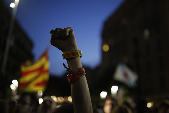 A Catalonian independence supporter wearing a bracelet with the "estelada" or pro independence flag colours, raises her fist during reactions after the vote in Barcelona, Spain, Sunday Sept. 27, 2015. Voters in Catalonia participated in an election Sunday that could propel the northeastern region toward independence from the rest of Spain or quell secessionism for years. Secessionists have long pushed for an independence referendum, but Spain's central government has not allowed one, arguing it would be unconstitutional because only it can call such a vote. (AP Photo/Emilio Morenatti).
