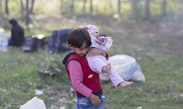 A Syrian refugee girl carries her sister as refugees rest at Sarayici Park, as they wait for permission to pass the Turkish-Greek border in Edirne, Turkey, 20 September 2015. 