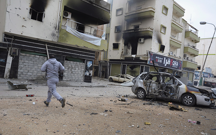 A man runs between buildings damaged during clashes between Libyan military soldiers and Islamic extremist militias in Benghazi, Libya, Thursday, Oct. 30, 2014.