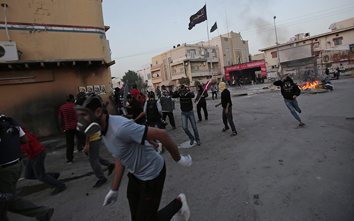 Bahraini anti-government protesters, some carrying national flags, run from an approaching armored police vehicle during clashes in Bilad Al Qadeem, Bahrain on Jan. 30, 2015.
