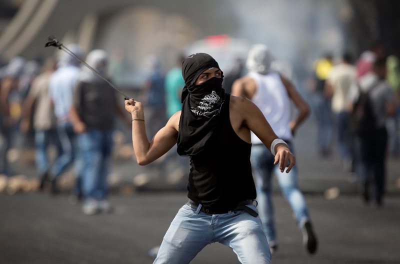 A Palestinian hurls a stone during clashes with Israeli troops near Ramallah, West Bank, Monday, Oct. 12, 2015.