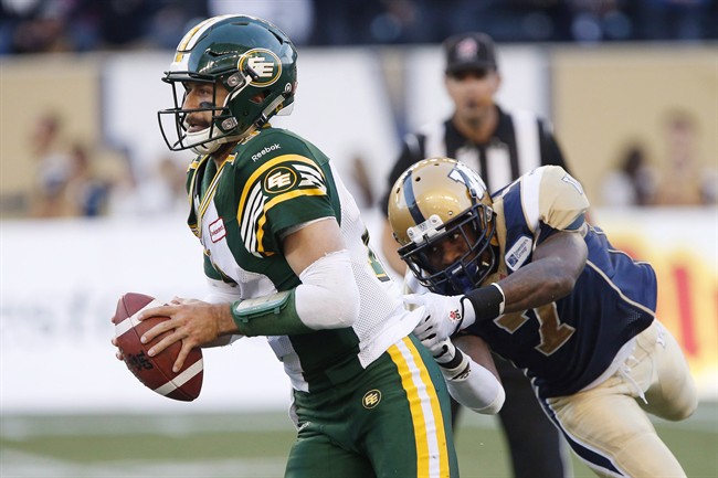 Edmonton Eskimos' quarterback Mike Reilly (13) gets away from Winnipeg Blue Bombers' Demond Washington (7) during the second half of CFL action in Winnipeg Saturday, October 3, 2015.
