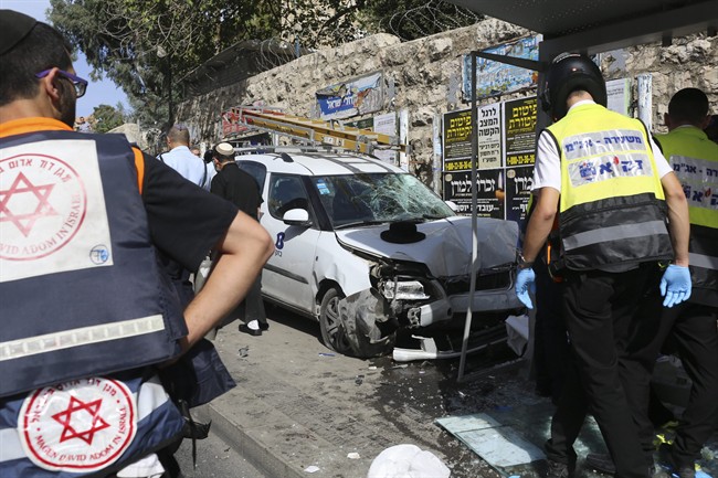 Police and emergency services respond to an attack in Jerusalem Tuesday, Oct. 13, 2015. A Palestinian rammed a vehicle into a bus stop then got out and started stabbing people killing one and wounding several others before he was shot dead, police said.