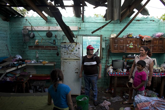 Josefina Magana Ruiz, center, surveys her home damaged by Hurricane Patricia, in La Fortuna, Mexico, Saturday, Oct. 24, 2015. Hurricane winds tore off much of the roof of the two-room home where seven people live, soaking mattresses and destroying belongings.