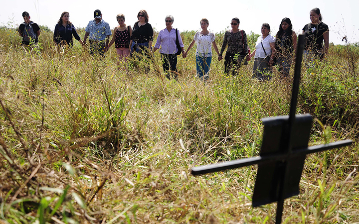 Relatives of missing people hold hands as they stand in an unofficial cemetery that is believed to have been used to bury about 150 bodies of crime victims near the town of Tetelcingo, Mexico, Friday, Nov. 6, 2015. 