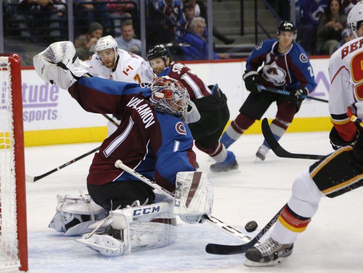 Colorado Avalanche goalie Semyon Varlamov, left, of Russia, deflects a shot off the stick of Calgary Flames center Sam Bennett during the second period of an NHL hockey game Tuesday, Nov. 3, 2015, in Denver.