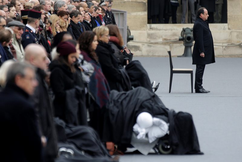 French President Francois Hollande, right, attends a ceremony to honor the 130 victims killed in the Nov. 13 attacks, in the courtyard of the Invalides in Paris, Friday, Nov. 27, 2015.