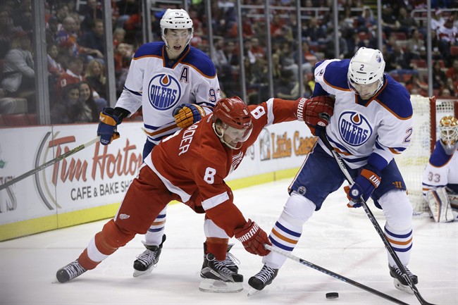 Detroit Red Wings left wing Justin Abdelkader (8) reaches for the puck next to Edmonton Oilers defenseman Andrej Sekera (2) of the Czech Republic during the second period of an NHL hockey game, Friday, Nov. 27, 2015, in Detroit. 