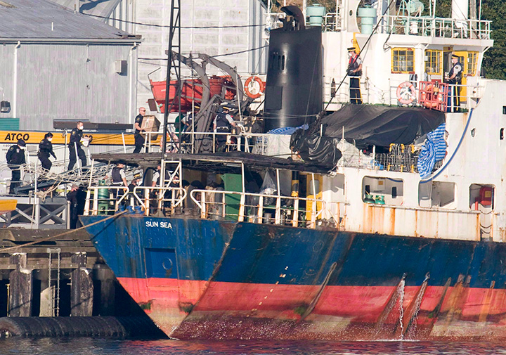 Police and military personnel wear surgical masks as they board the MV Sun Sea after it was escorted into CFB Esquimalt in Colwood, B.C. on Aug. 13, 2010. 