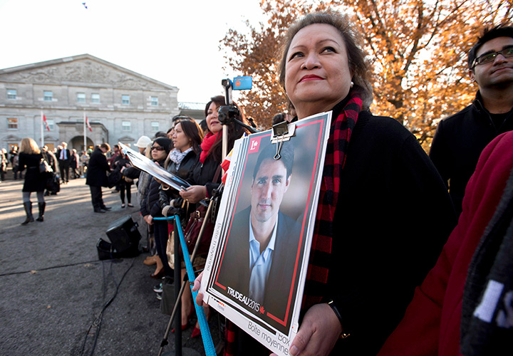 A member of the public holds a Justin Trudeau campaign poster before the swearing-in ceremony of Prime Minister-designate Justin Trudeau at Rideau Hall in Ottawa on Wednesday, Nov. 4, 2015.