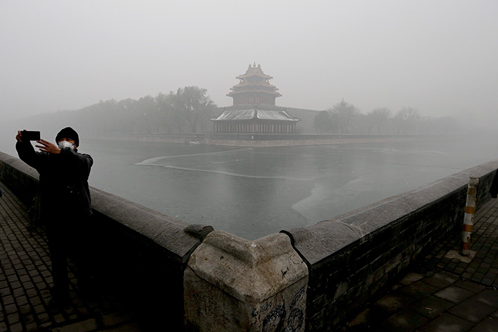 A man wearing a mask to protect himself from pollutants takes a selfie near the Turret of the Forbidden City on a heavily polluted day in Beijing, Tuesday, Dec. 1, 2015.
