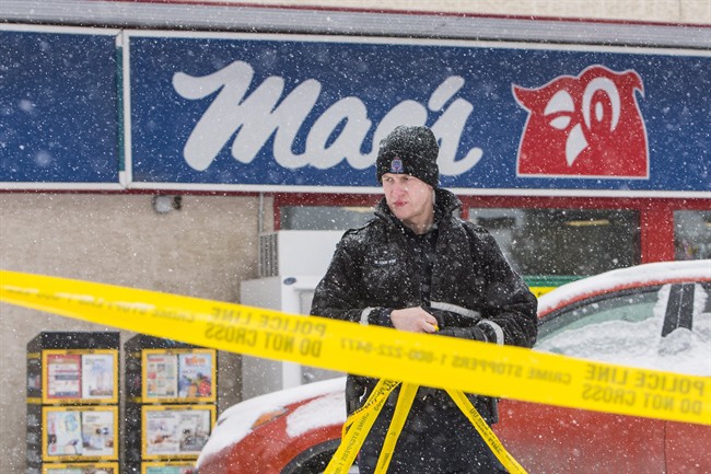A police member removes crime scene tape at a Mac’s convenience store in Edmonton on Friday, December 18, 2015.