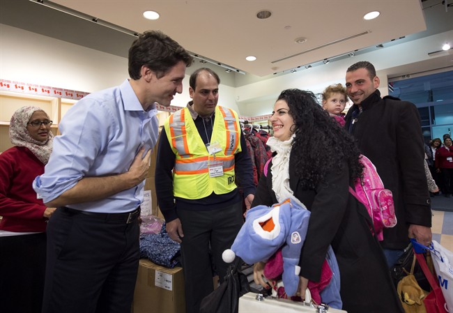 Canadian Prime Minister Justin Trudeau greets a family of refugees from Syria as they arrive at Pearson International airport, in Toronto, on Friday, Dec. 11, 2015.