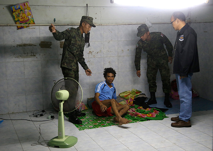 In this Monday, Nov. 9, 2015 photo, Thai soldiers and a member of the Department of Special Investigation wake up a worker during a raid on a shrimp shed in Samut Sakhon, Thailand.