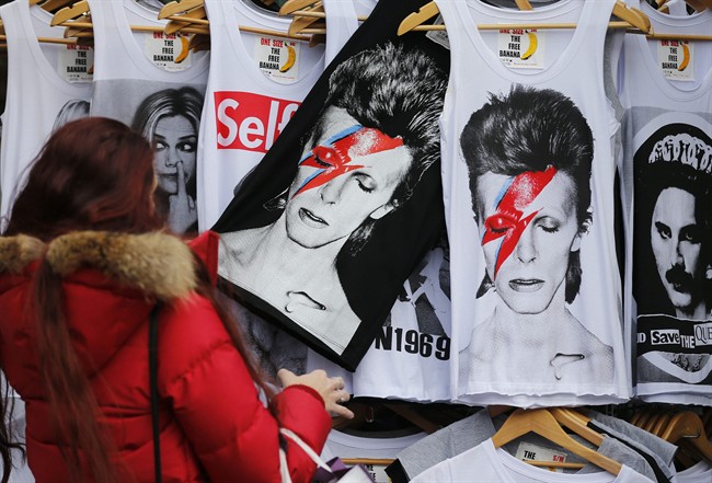 A woman looks at shirts with a portrait of David Bowie, in London, Monday, Jan. 11, 2016.
