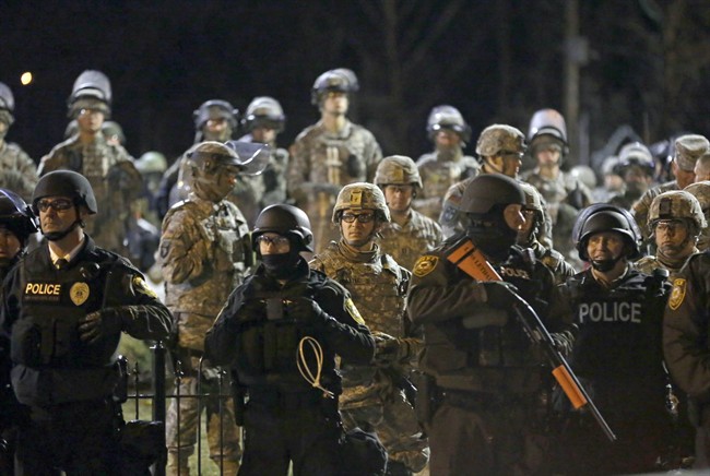 In this Friday, Nov. 28, 2014, file photo, police and Missouri National Guardsmen face protesters gathered in front of the Ferguson Police Department in Ferguson, Mo.