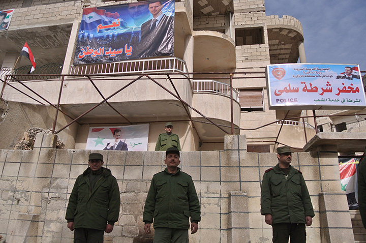 Syrian troops stand in front of a police station with a portrait of Syrian President Bashar Assad in Salma, Syria, Friday, Jan. 22, 2016. 