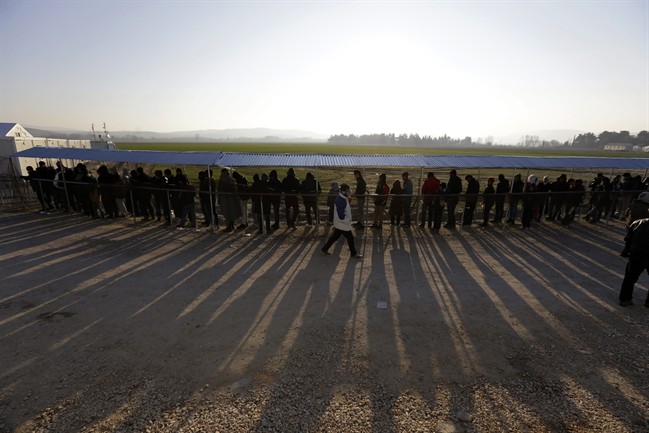 People form a line as they wait to receive food distributed by non-governmental organizations at a refugee camp in the northern Greek village of Idomeni Thursday, Jan. 21, 2016. About 1,000 refugees from Syria, Afghanistan and Iraq are stranded at Greece's northern border with Macedonia, after Macedonian authorities stopped letting them through citing problems with transit flows further north on the Balkan route which have caused a chain reaction. (AP Photo/Thanassis Stavrakis).