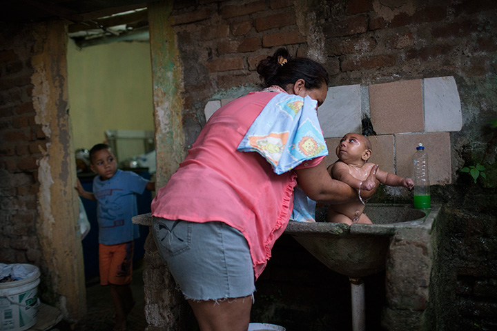 In this Jan. 30, 2016 photo, Solange Ferreira bathes Jose Wesley in a sink in their house in Bonito, Pernambuco state, Brazil.
