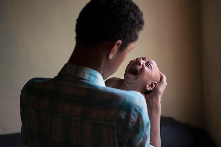 In this Jan. 30, 2016 photo, Elielson tries to calm down his baby brother Jose Wesley, in Bonito, Pernambuco state, Brazil.