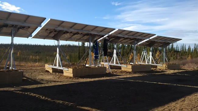 A worker adjusts one of the panels on a solar array installed in this tiny, remote northern community of Colville Lake, N.W.T., in this undated handout photo. Colville Lake expects to run entirely on the sun as summer returns – with batteries and a diesel generator as a backup.