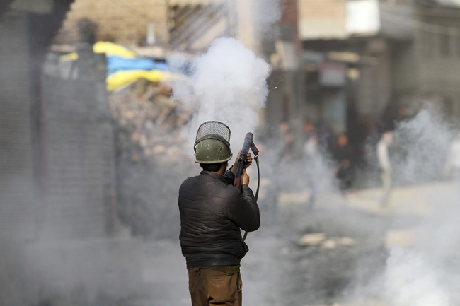 An Indian policeman fires tear smoke shell on protesters during a clash in Srinagar, Indian controlled Kashmir, Monday, Feb. 15, 2016.