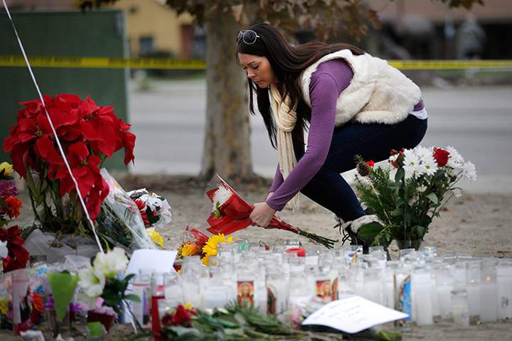 Jennifer Caballero places flowers at a makeshift memorial honouring the victims of the San Bernardino shooting rampage, Friday, Dec. 4, 2015, in California. 