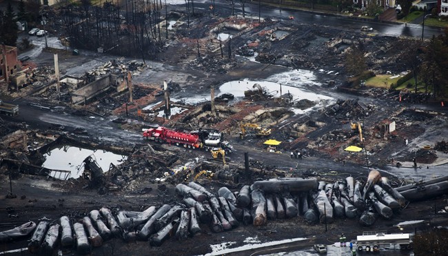 In this July 9, 2013 file photo, workers comb through debris after a train derailed causing explosions of railway cars carrying crude oil in Lac-Megantic, Quebec. A government watchdog says federal regulators are failing to refer serious safety violations involving freight rail shipments of crude oil for criminal prosecution.