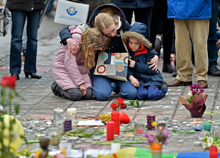 A woman and children sit and mourn at the Place de la Bourse in the centre of Brussels, for the victims of Tuesday’s bombings, on Wednesday, March 23, 2016.