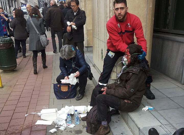 A private security guard helps a wounded women outside the Maalbeek subway station in Brussels on March 21, 2016 after a blast near the EU institutions.