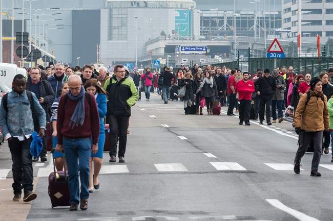 People walk away from Brussels airport after explosions rocked the facility in Brussels, Belgium Tuesday March 22, 2016. (AP Photo/Geert Vanden Wijngaert)