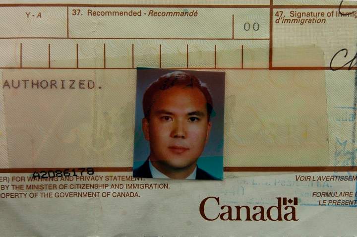 A demonstrator holds an immigration document bearing the photograph Huseyin Celil of during a protest for his release in front of the Chinese Consulate in Toronto, Ont. on November 2006.