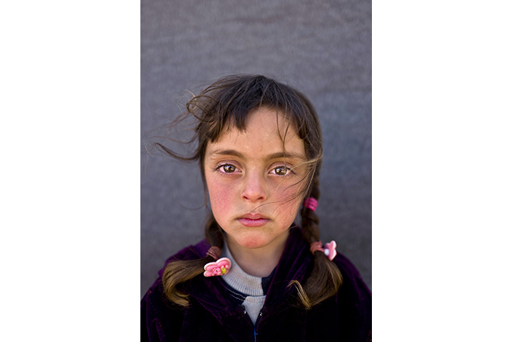 In this Friday, March 11, 2016 photo, Syrian refugee girl Zahra Mahmoud, 5, from Deir el-Zour, Syria, poses for a picture at an informal tented settlement near the Syrian border on the outskirts of Mafraq, Jordan.