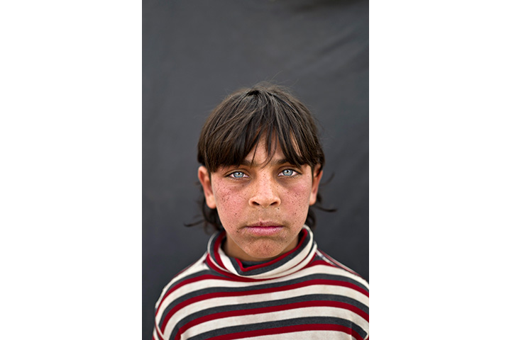 In this Saturday, March 12, 2016 photo, Syrian refugee boy Rakan Raslan, 11, from Hama, Syria, poses for a picture at an informal tented settlement near the Syrian border on the outskirts of Mafraq, Jordan.