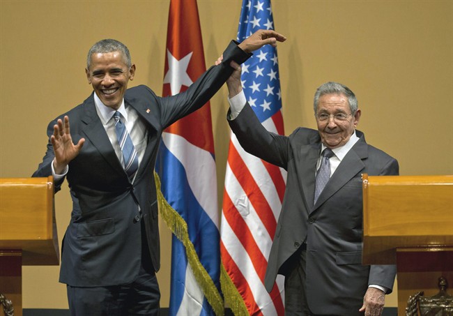In this Monday, March 21, 2016 photo, Cuban President Raul Castro, right, lifts up the arm of President Barack Obama at the conclusion of their joint news conference at the Palace of the Revolution in Havana, Cuba.