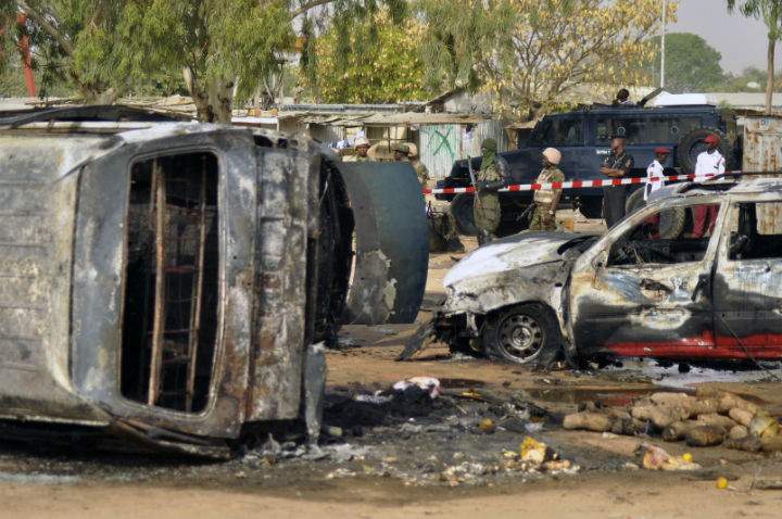 In this Tuesday Feb. 24, 2015 file photo, police officers stand guard following a suicide bomb explosion at a bus station in Kano, Nigeria.