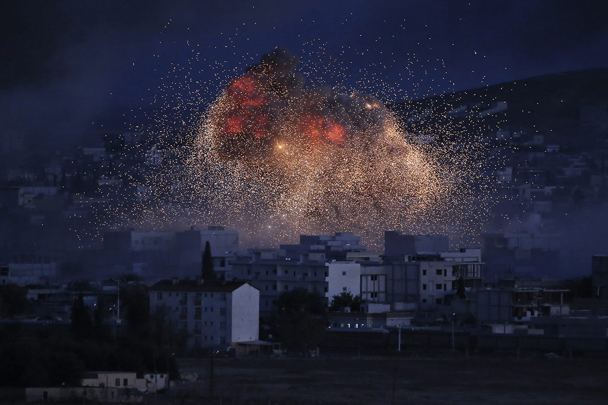 In this Oct. 20, 2014 file photo, thick smoke and flames erupt from an airstrike by the U.S.-led coalition in Kobani, Syria, as seen from a hilltop on the outskirts of Suruc, at the Turkey-Syria border. 