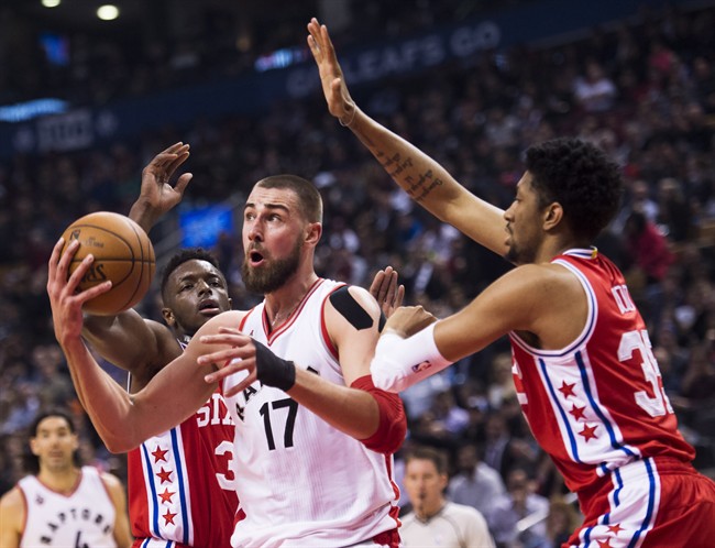 Toronto Raptors centre Jonas Valanciunas (17) moves the ball past Philadelphia 76ers forward Christian Wood (35) and 76ers forward Robert Covington (33) during first half NBA basketball action in Toronto on Tuesday, April 12, 2016. THE CANADIAN PRESS/Nathan Denette.