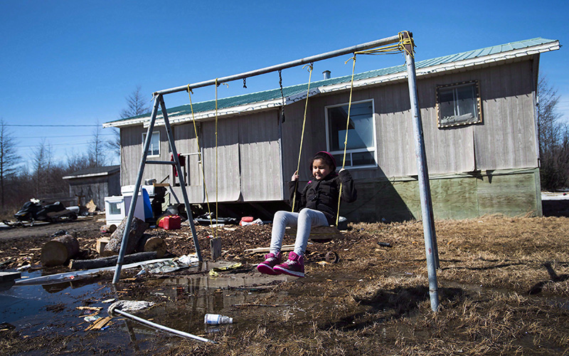 Eight-year-old Shakira Koostachin plays on a swing in the northern Ontario First Nations reserve in Attawapiskat, Ont., on Tuesday, April 19, 2016. 