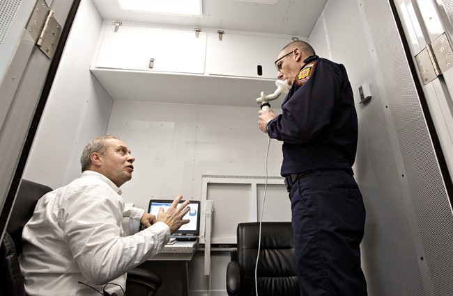 Dr. Jeremy Beach, left, tests the lung function of firefighter captain Kelly Lehr with a spirometer at a fire hall in Sherwood Park, Alta., on Wednesday, May 18, 2016. University of Alberta researcher Nicola Cherry set up a mobile lab to test firefighters for breathing problems after returning from Fort McMurray.
