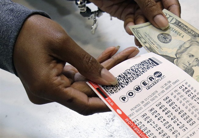 In this Jan. 13, 2016 file photo, a clerk hands over a Powerball ticket for cash at Tower City Lottery Stop in Cleveland.