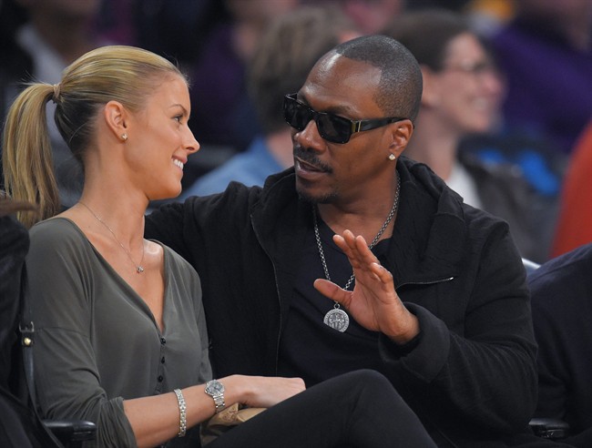 FILE - In this April 12, 2015, file photo, actor Eddie Murphy talks with his girlfriend Paige Butcher during an NBA basketball game between the Los Angeles Lakers and the Dallas Mavericks. 