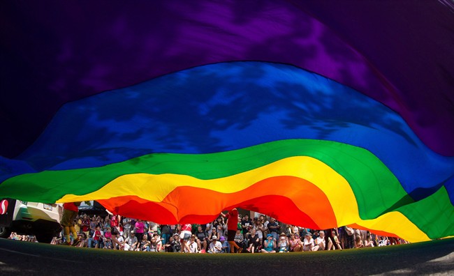 A large rainbow flag is carried down Robson Street during the Vancouver Pride Parade in Vancouver, B.C., on Sunday, August 2, 2015.
