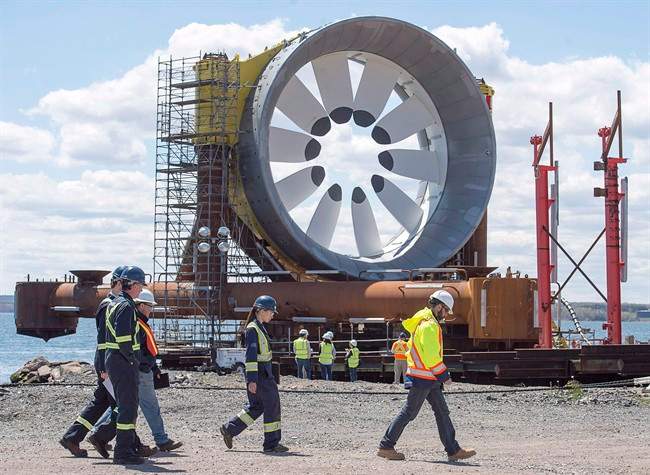 Workers head past a turbine for the Cape Sharp Tidal project at the Pictou Shipyard in Pictou, N.S., on Thursday, May 19, 2016. The need for more consultation and permits has temporarily pulled the plug on plans to install the first of two towering turbines designed by Cape Sharp Tidal to harness the power of the Bay of Fundy.THE CANADIAN PRESS/Andrew Vaughan.